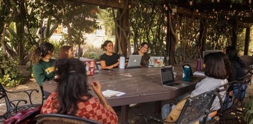 Students talk and work in an outdoor classroom by the Grove House